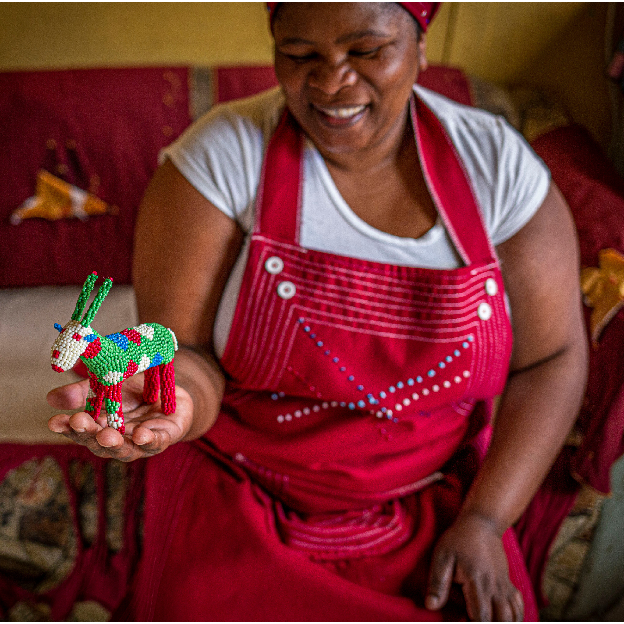Craftswoman holding a handmade Monkeybiz beaded animal 