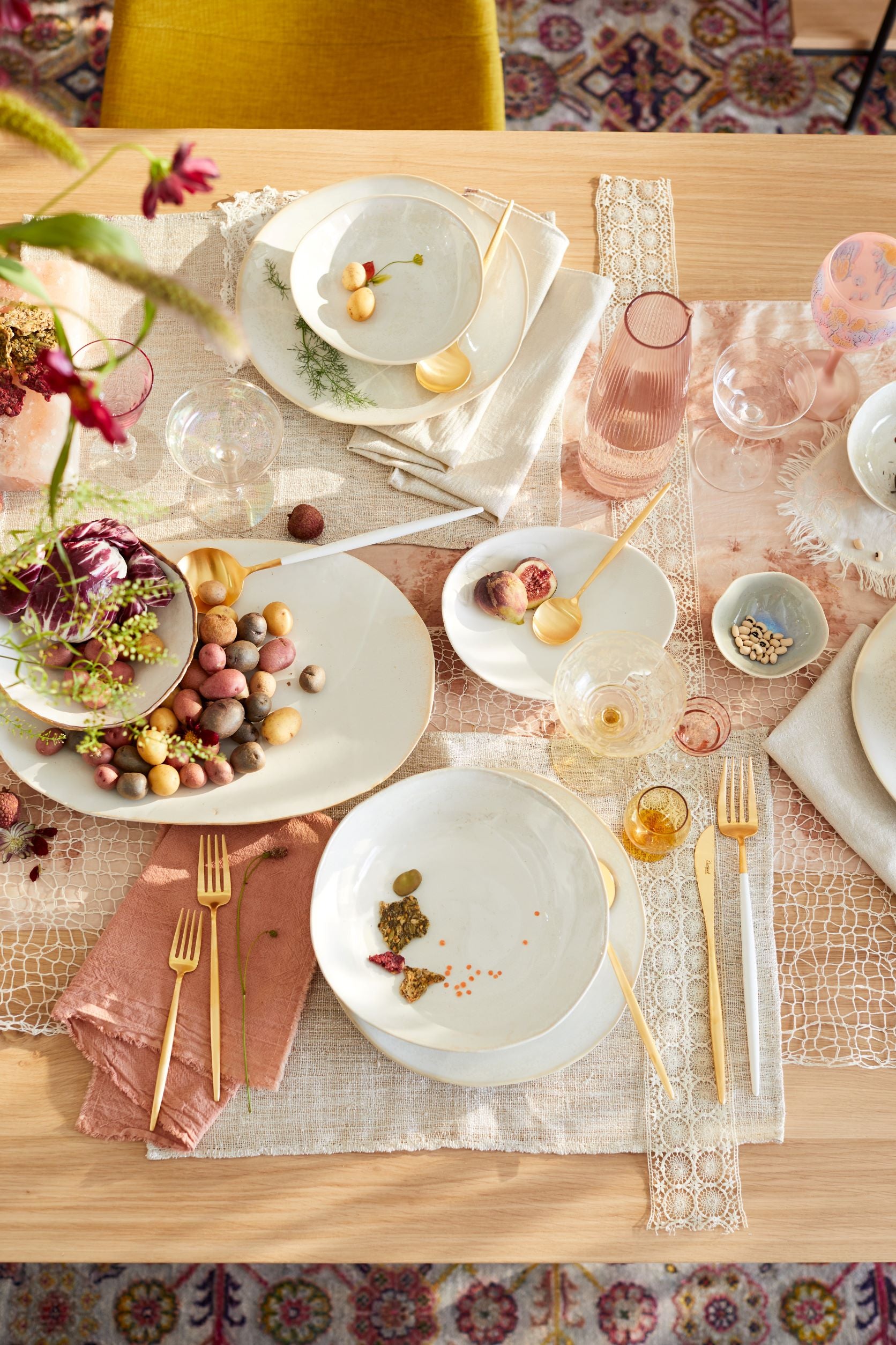Tablescape with pink linens, white dishes, and gold silverware