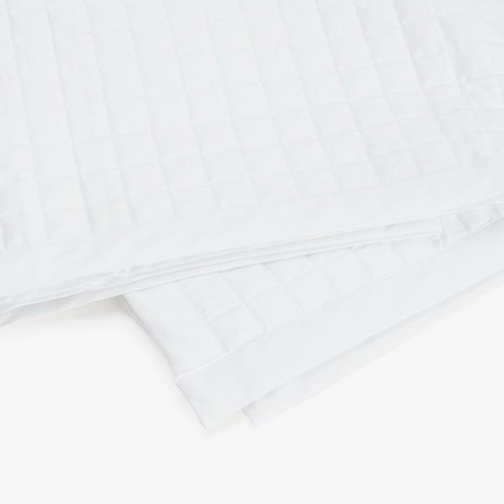 White quilted blanket with stitched squares for insulation and comfort.