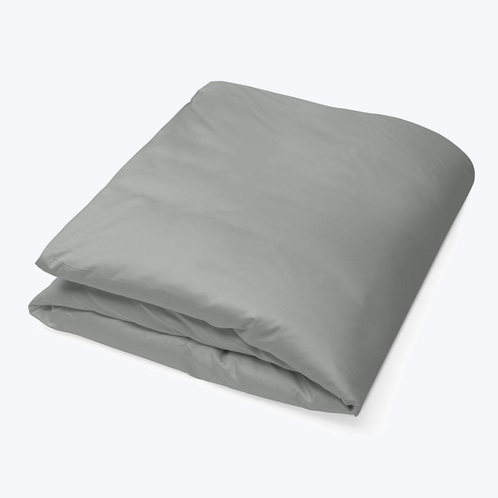 Neatly folded grey duvet cover on white surface, modern aesthetic.