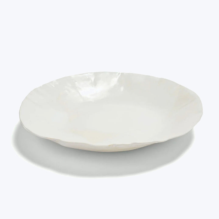 Minimalist white ceramic plate with organic edge profile on display.