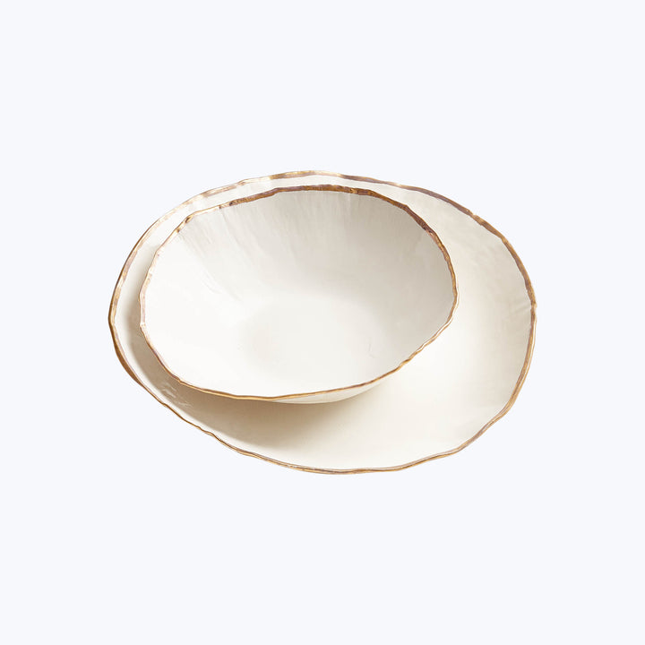 Elegant off-white ceramic dishes with gold trim in stack.