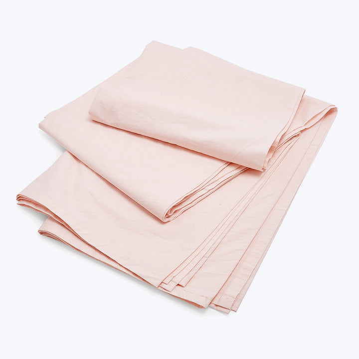 Neatly folded light pink flat sheet on white background.