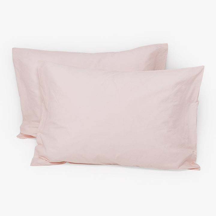 Two pale pink rectangular pillows neatly positioned against white background.