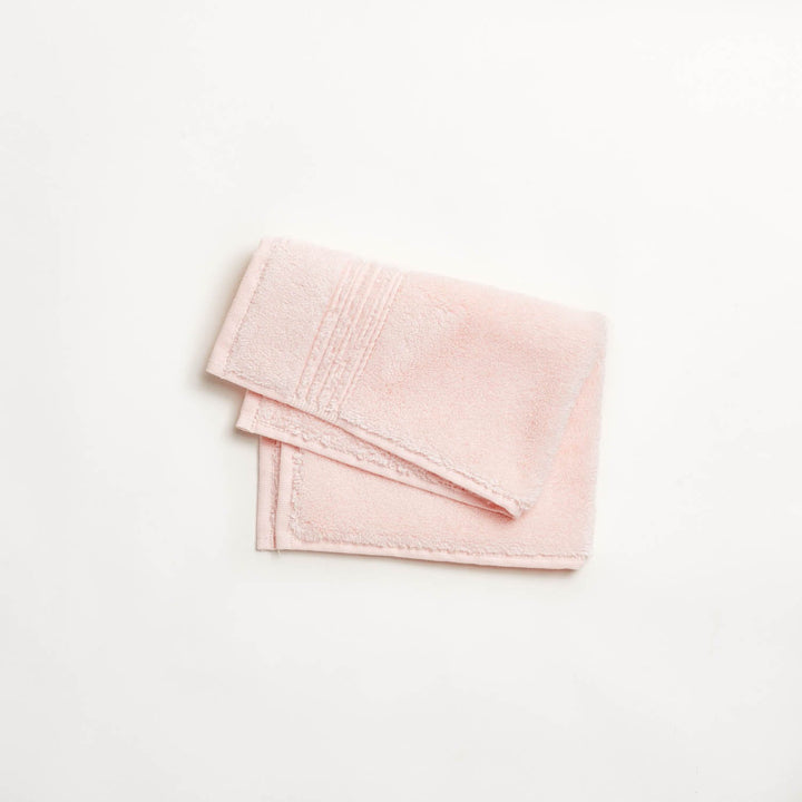 Soft plush pale pink towel folded on white background.