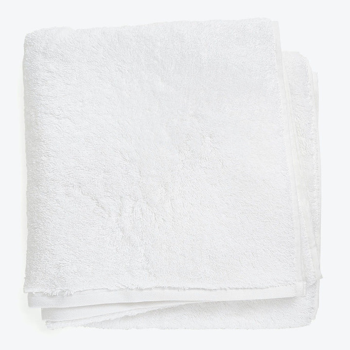 Soft, fluffy white bath towel with simple hem, clean design.
