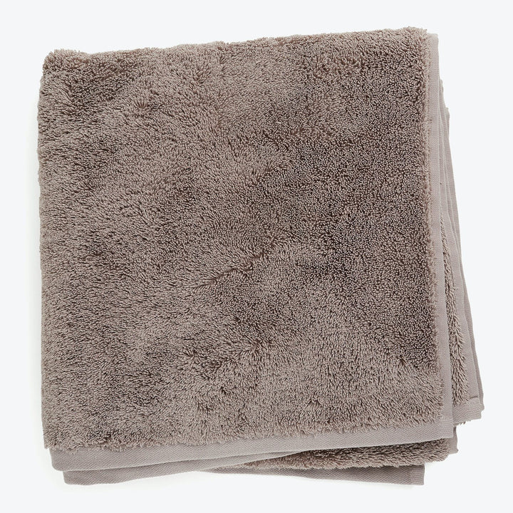 High-quality taupe plush towel with neatly trimmed edges displayed folded