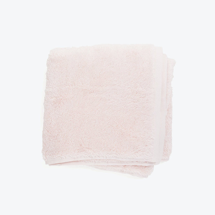 Soft and fluffy pale pink terry cloth towel folded neatly.