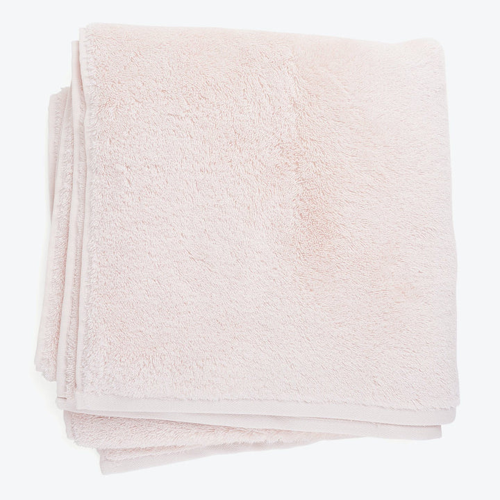 Soft, fluffy light pink towel folded neatly on white background.