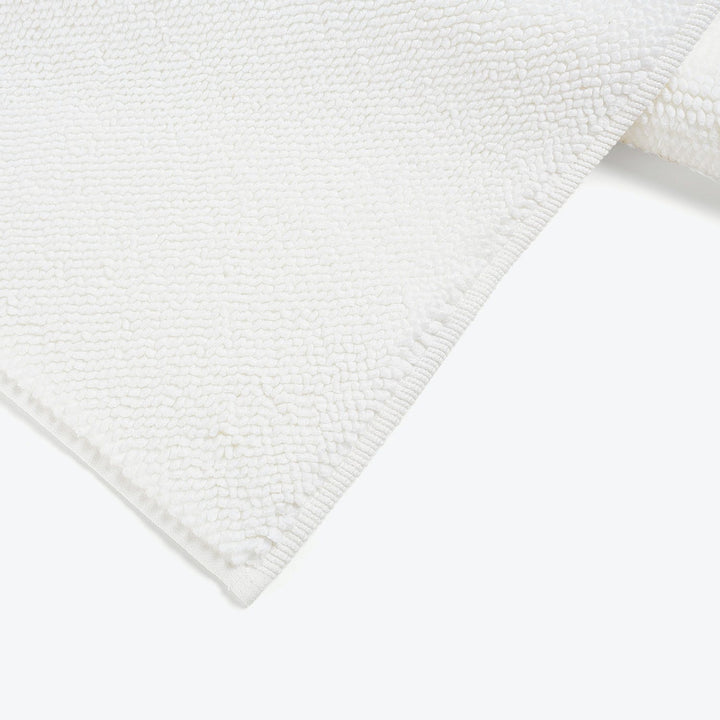 Plush white textured rug with raised bumps on bright background.