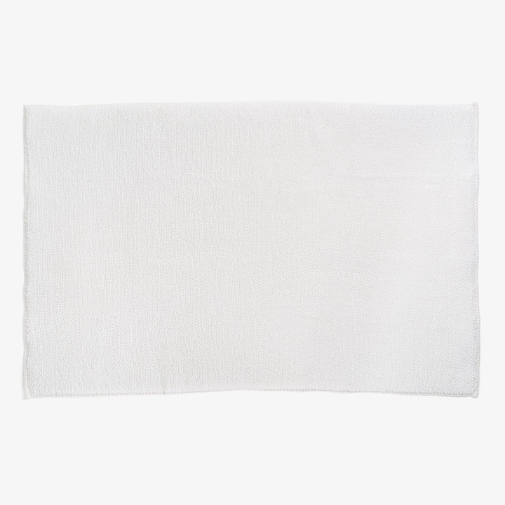 Plain white terrycloth towel with neatly hemmed edges laid flat.
