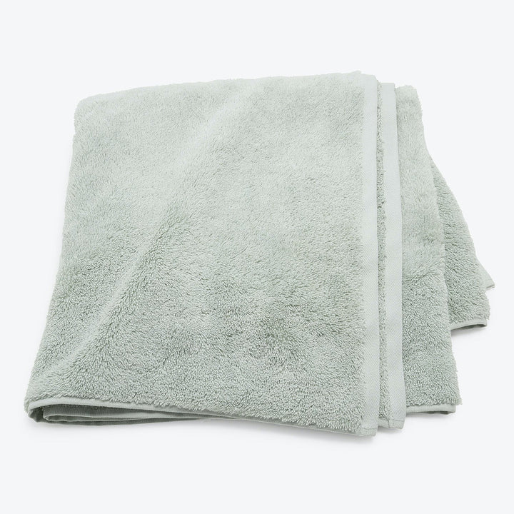 Stack of three soft, plush light green cotton towels folded.