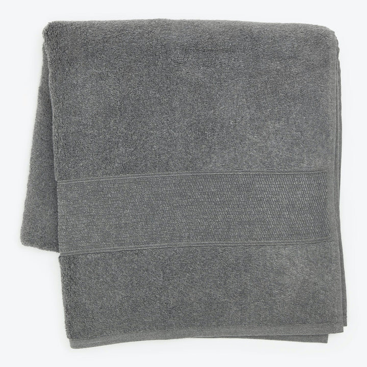 Neatly folded gray towel with decorative band on white background.