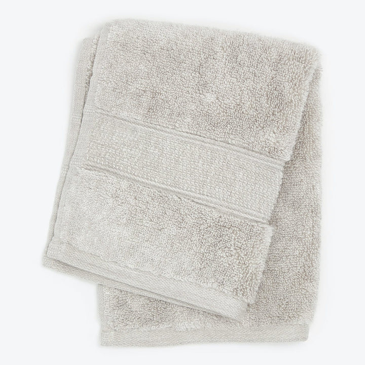 Freshly laundered light grey terrycloth bath towel with ribbed texture.