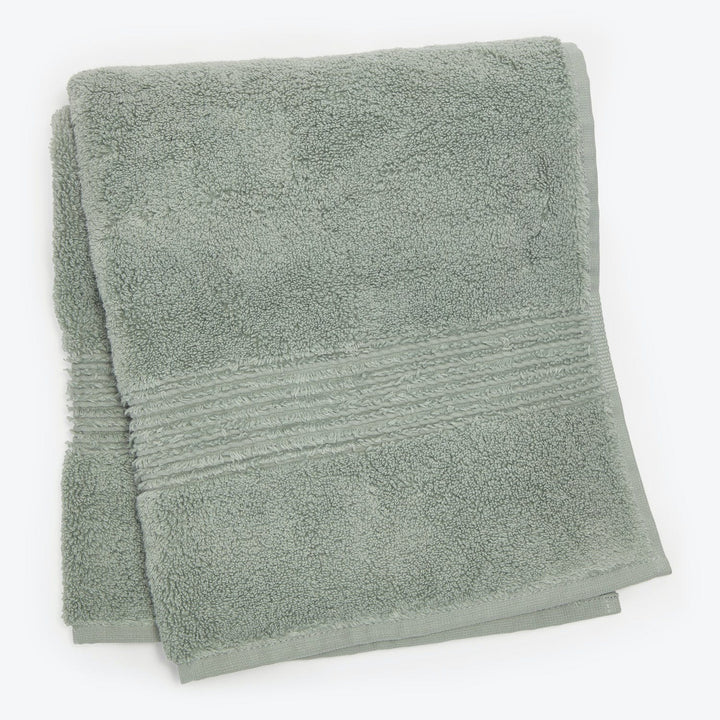 Soft, fluffy light green bath towel with decorative border folded.