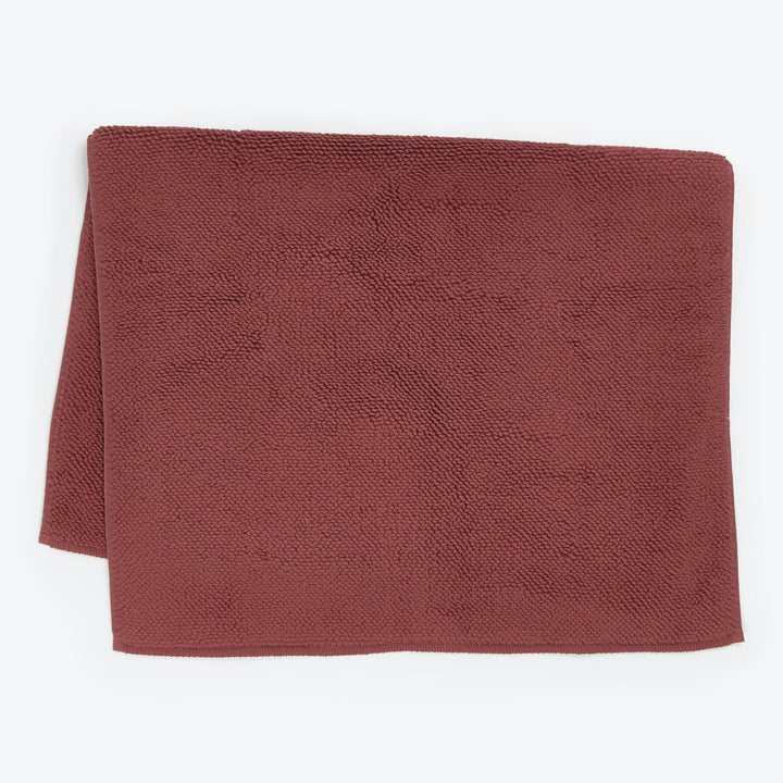 Folded terracotta towel with textured surface on white background.