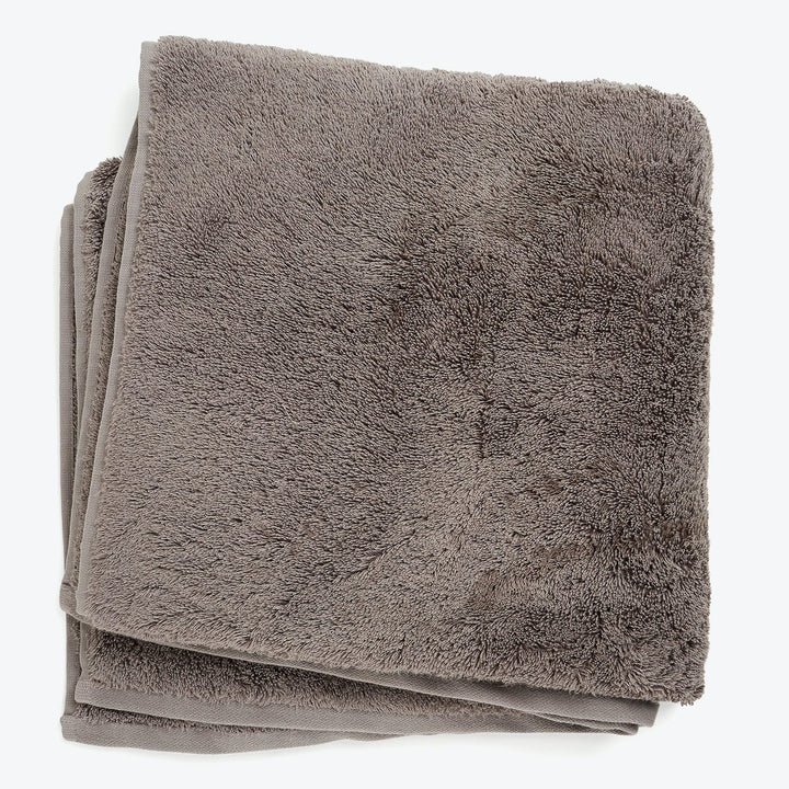 Soft and fluffy taupe bath towel neatly folded on white
