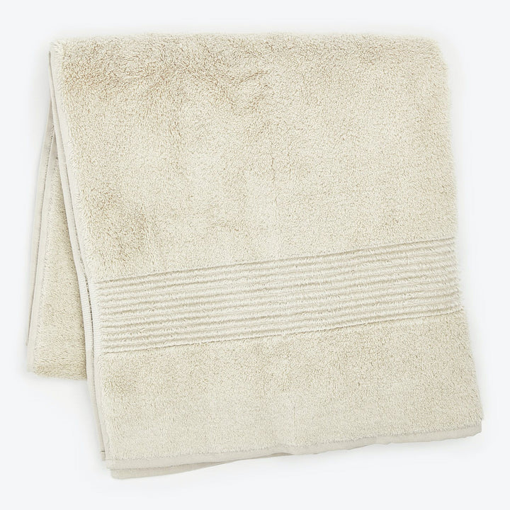 Soft and fluffy beige bath towel with decorative ridging detail.