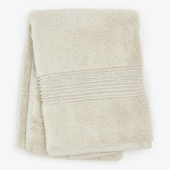 Neatly folded beige bath towel with decorative ribbed texture.