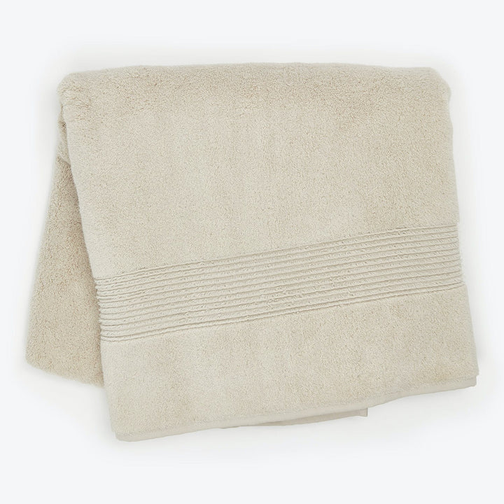 Beige terry cloth bath towel with ribbed decorative band detail.