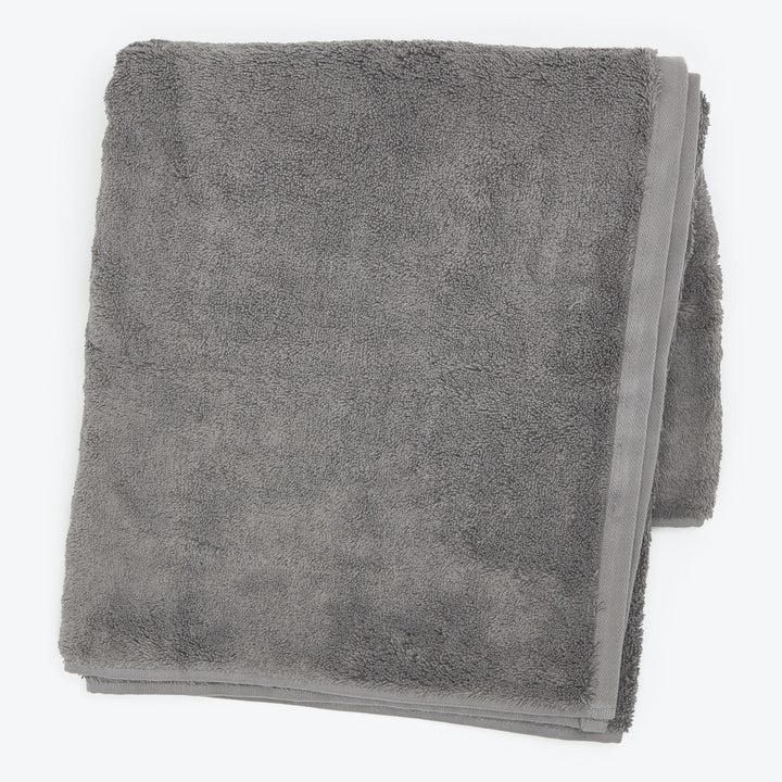 Soft, fluffy gray terry cloth towel neatly folded on white.