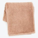 Soft, fluffy, light brown towel neatly folded on white background.