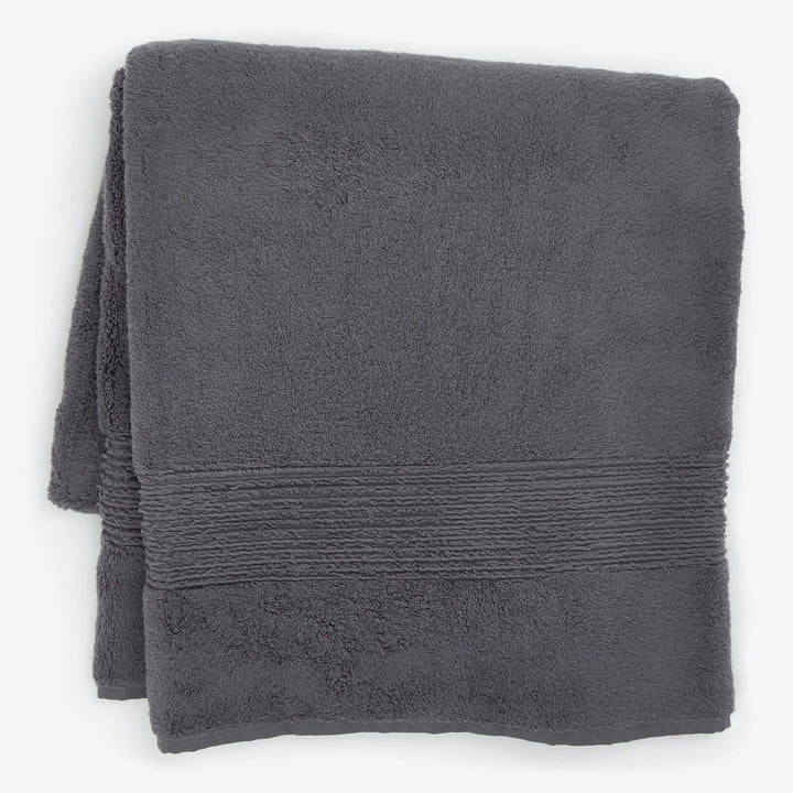 Neatly folded dark gray bath towel with decorative rib pattern.