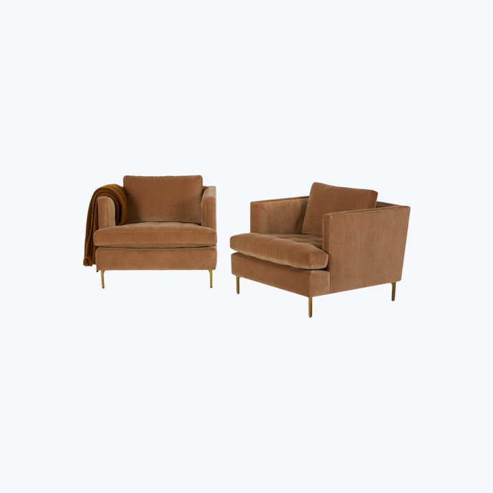 Pair of brown velvet armchairs with golden metal legs, cozy throw.