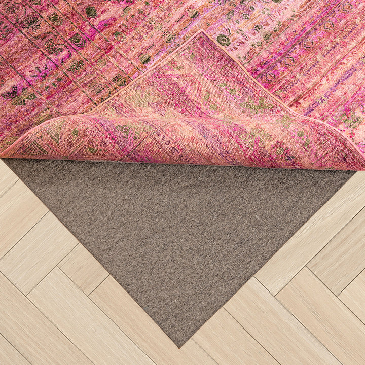 Vibrant patterned carpet partially rolled up to reveal hardwood floor.
