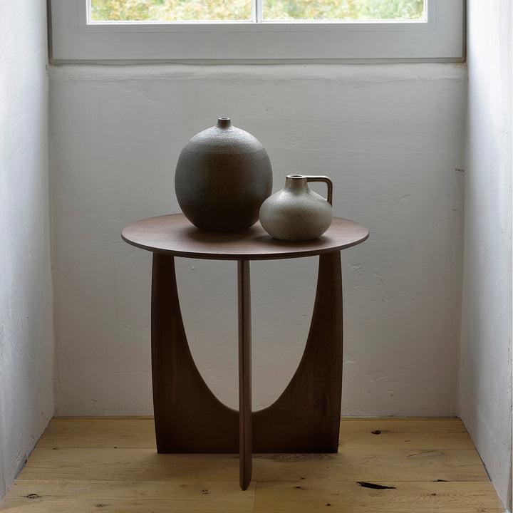 Minimalist interior with unique table, ceramic vessels, and natural light.