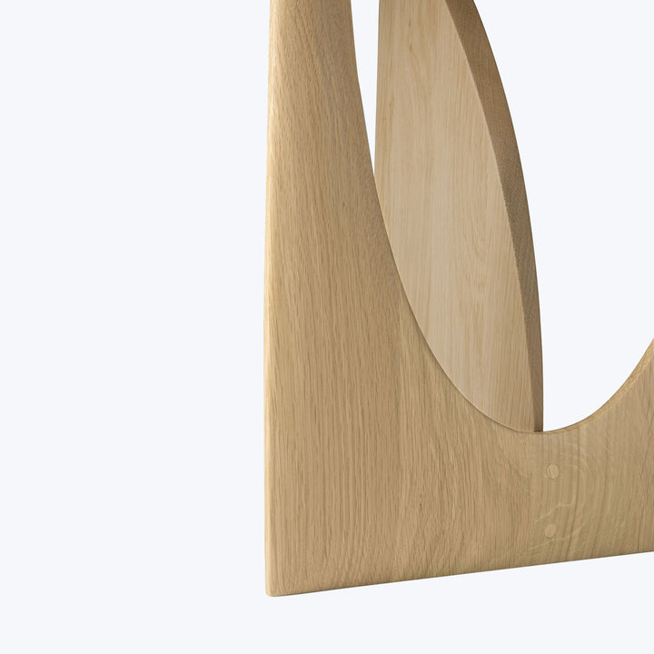 Smooth, light-colored wooden object with elegant curvilinear form and grain.