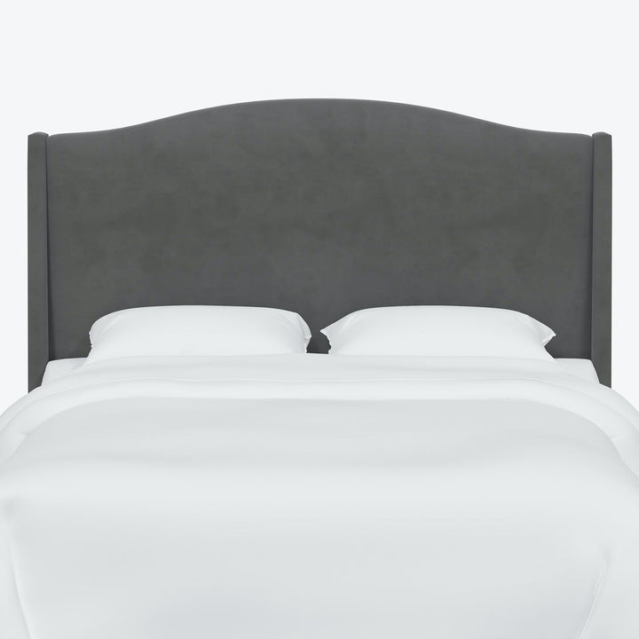 Freshly made bed with modern grey headboard and white bedding.