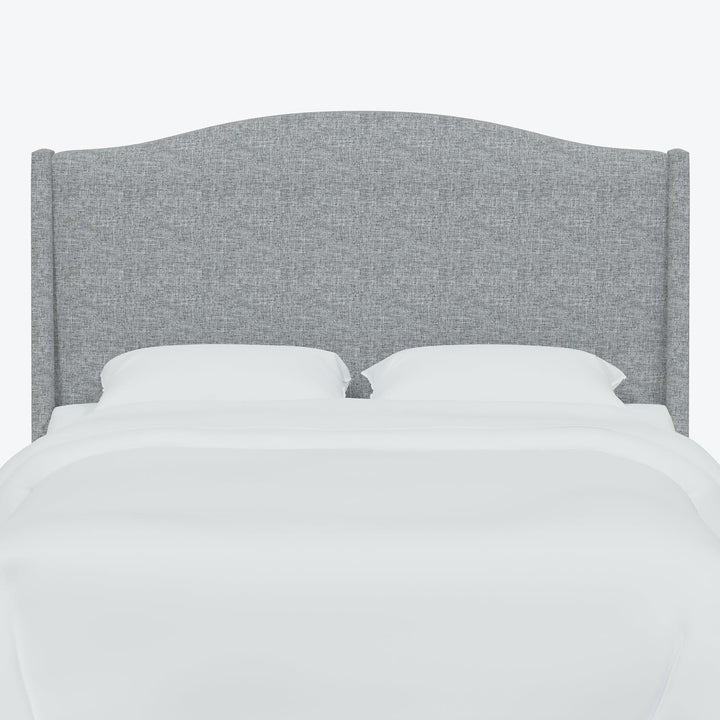 Minimalistic bed with gray upholstered headboard styled with white bedding.