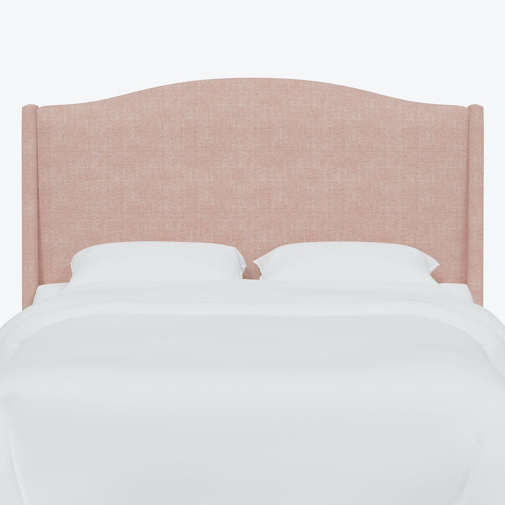 Serene bedroom setting showcased with a stylish, pinkish-tan upholstered headboard.
