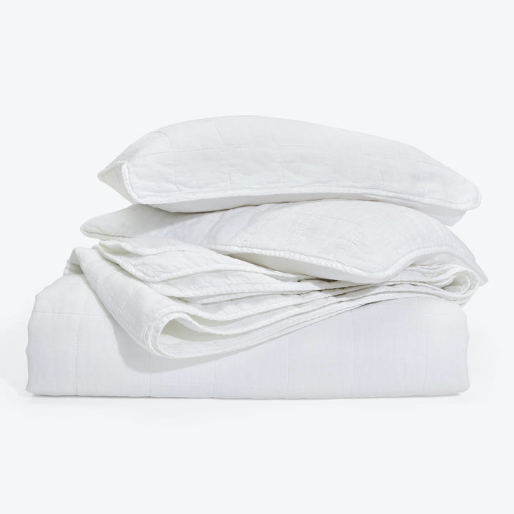 Clean, crisp white bedding set with pillows and duvet folded.