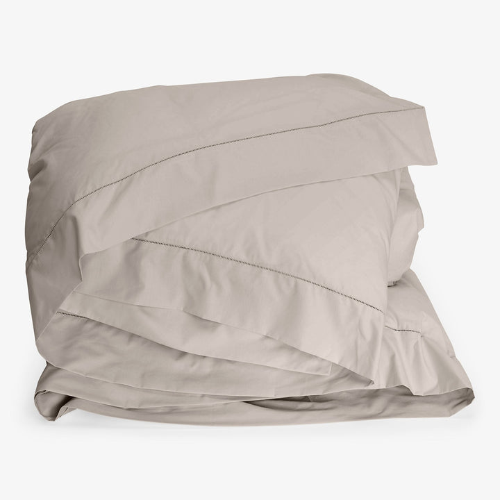 Freshly folded light gray bed linens with clean, modern design.