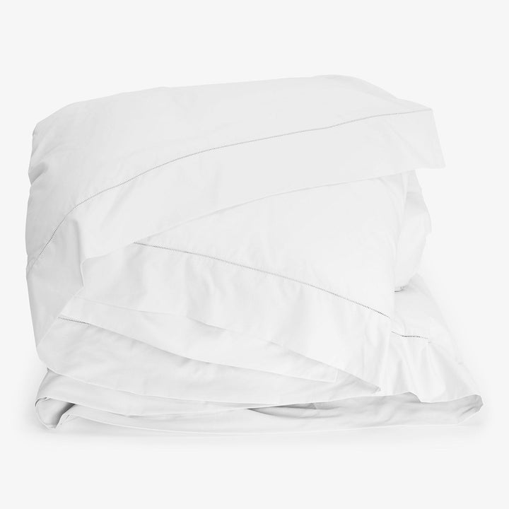 Neatly folded white duvet against plain background, stitching visible.