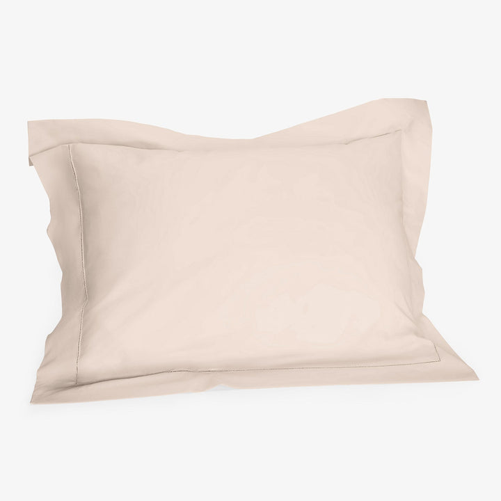 Cream pillowcase with flange detail on white background, soft texture.