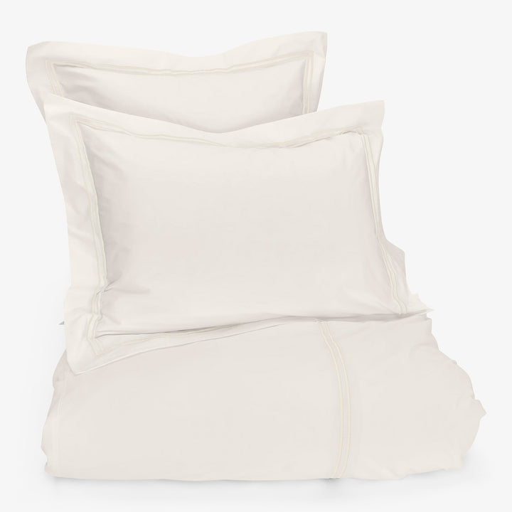 Minimalist, light-colored bedding set with soft, comfortable fabric textures.