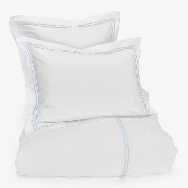 White bedding set with light blue accents for tranquil bedroom.