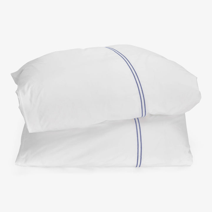 Minimalistic white pillows with blue lines on white background.