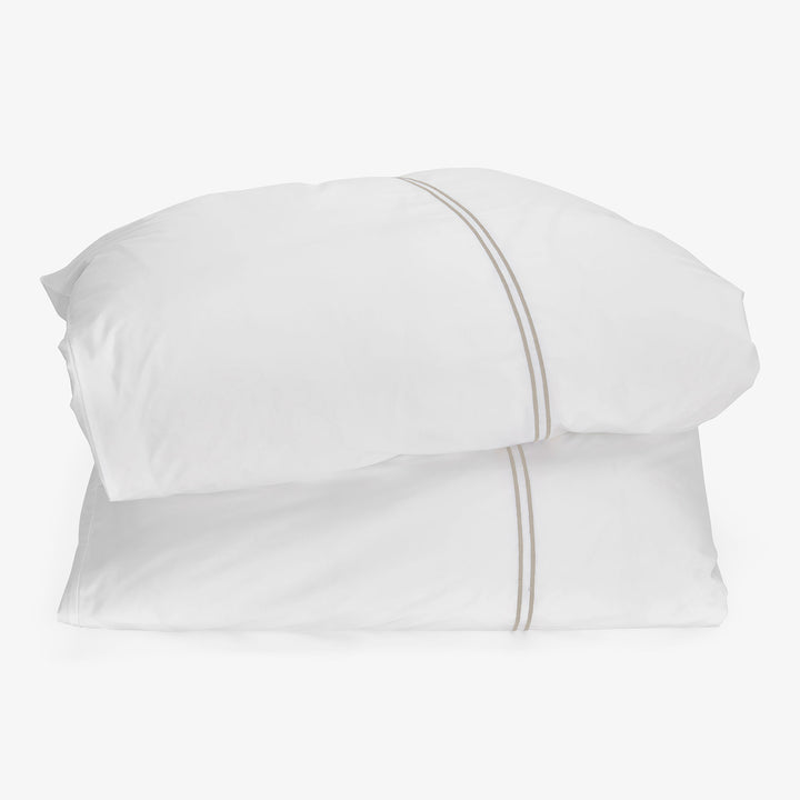 Elegant stacked pillows with decorative edge on white background display.