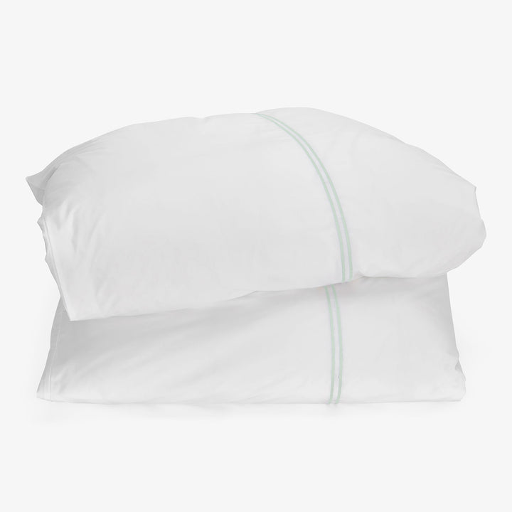 Two white pillows in crisp pillowcases with green stitching detail