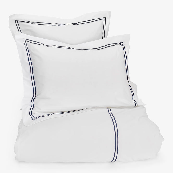 Elegant white bedding set with navy blue piping detail.