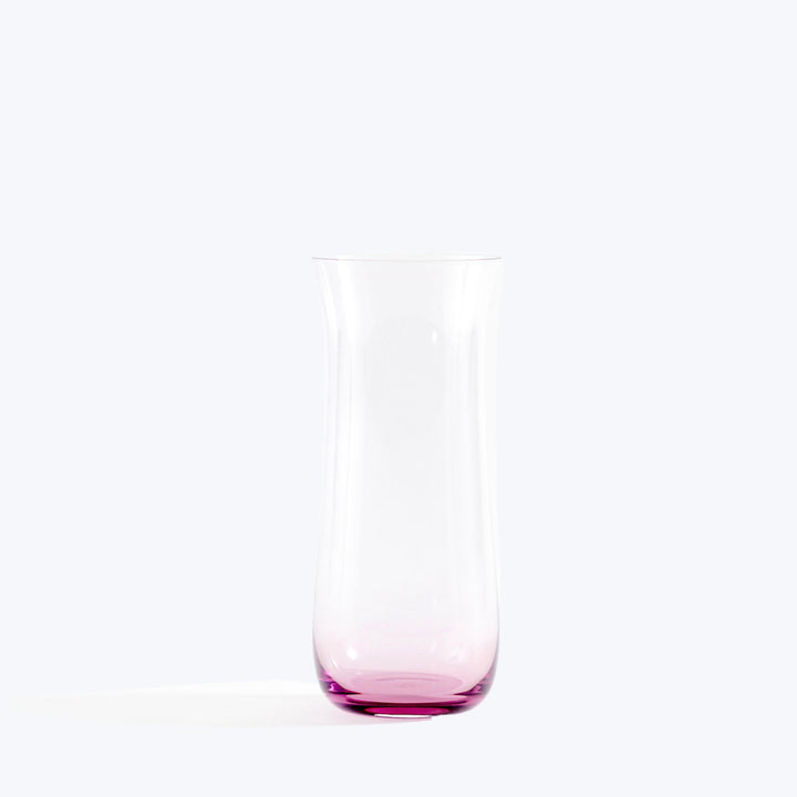 Minimalist glass vase with pink tint on white background.