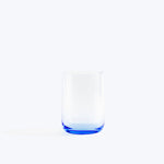 Empty blue tinted drinking glass on white background with shadow.
