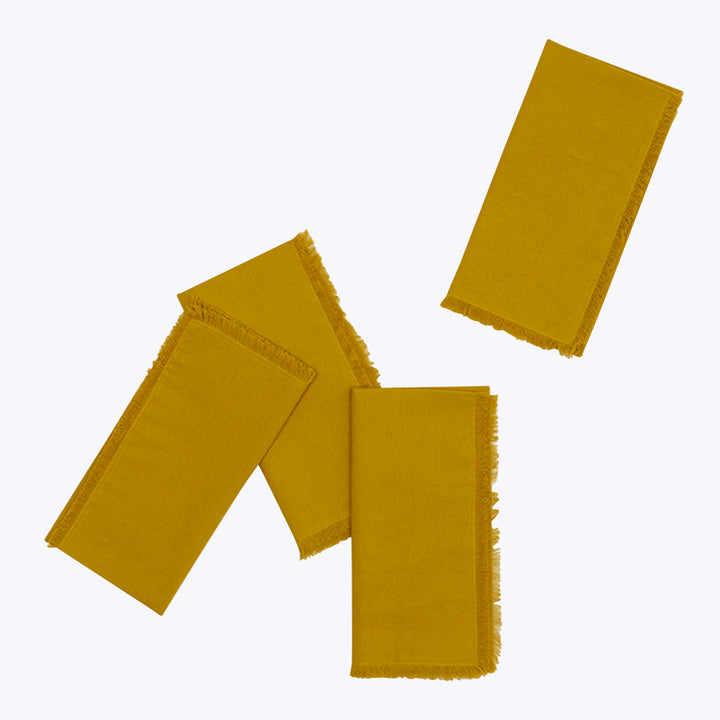 Overlapping mustard yellow cloth napkins with frayed edges on display.
