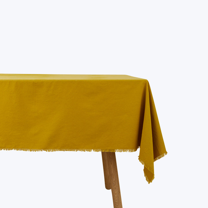 Simple wooden table with mustard yellow tablecloth and modern style