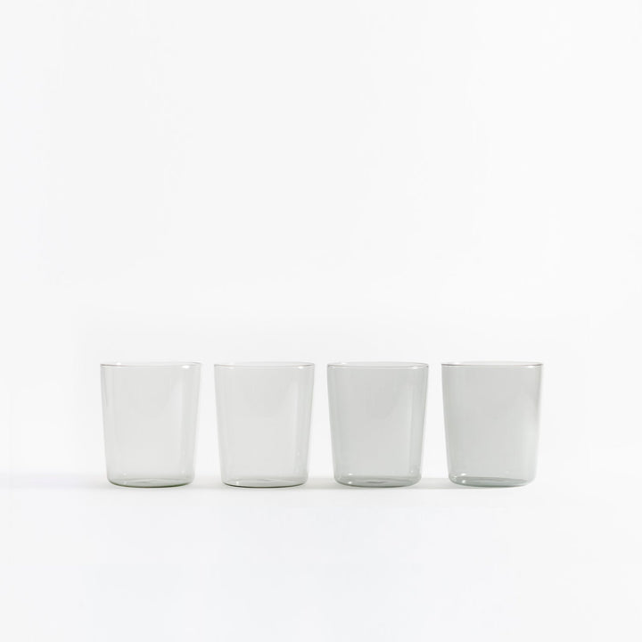 Four clear glasses in a row on white background