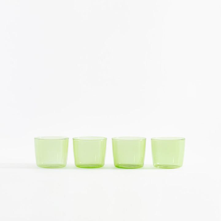 Four green translucent shot glasses arranged in a straight line.